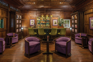 bar setting with green and deep purple chairs and wooden walls